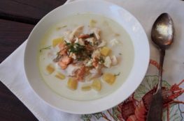 fish soup in a white plate with silver spoon and white napkin