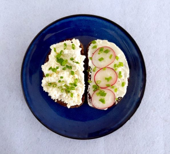 Rye bread open sandwich with cottage cheese and radishes on a blue plate