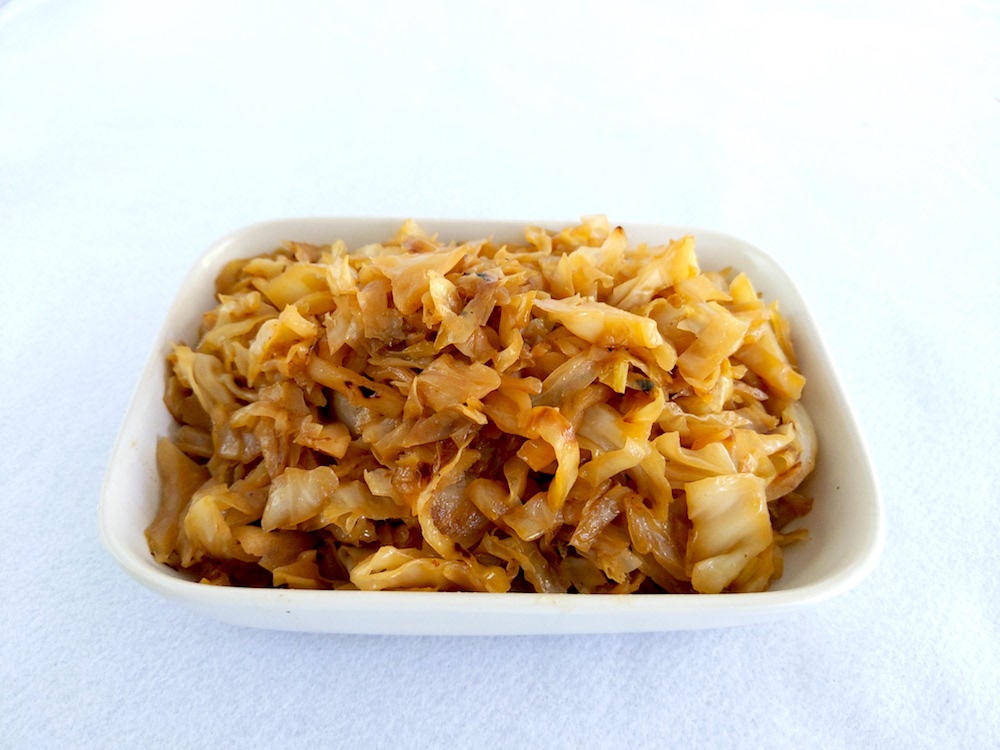 Plate of stewed cabbage on a white background