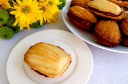 Madeleine shaped cookies with condensed milk caramel filling onawhite plate and yellow flavour background