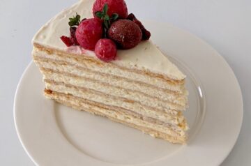 Honey cake on a white plate with red berry garnish