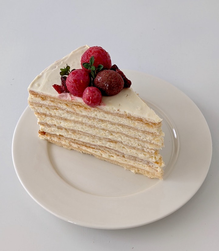Honey cake on a white plate with red berry garnish