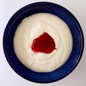 Semolina porridge in a blue bowl with red jam in the middle