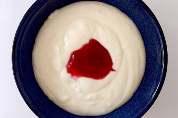 Semolina porridge in a blue bowl with red jam in the middle